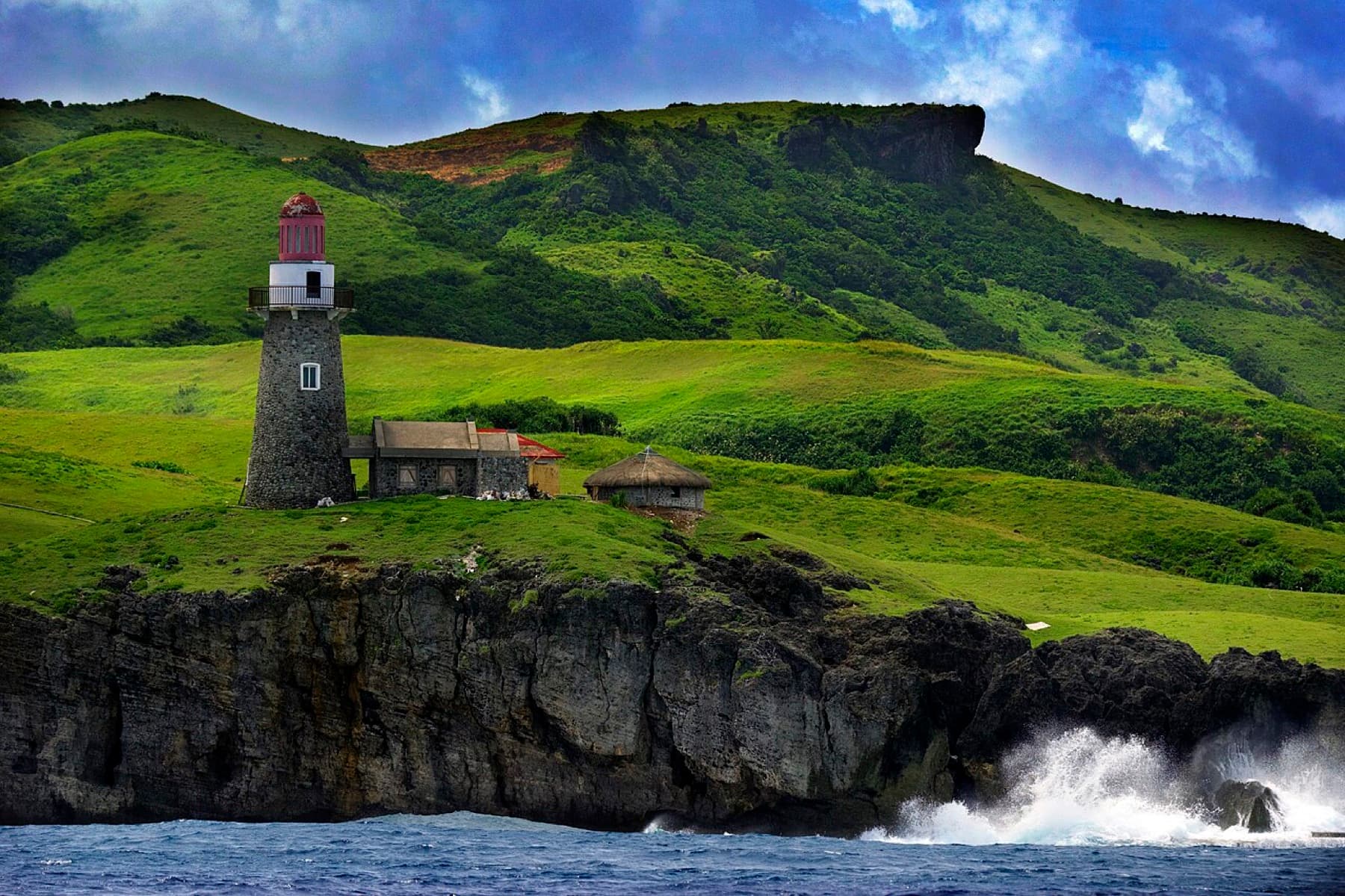 Lighthouse overlooking the green hills and sea of Batanes